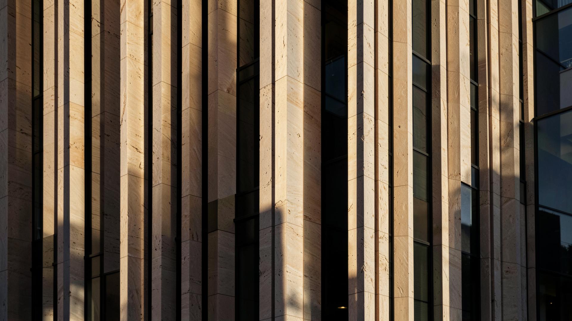 Vertical stone fins on a modern building facade in raking light.