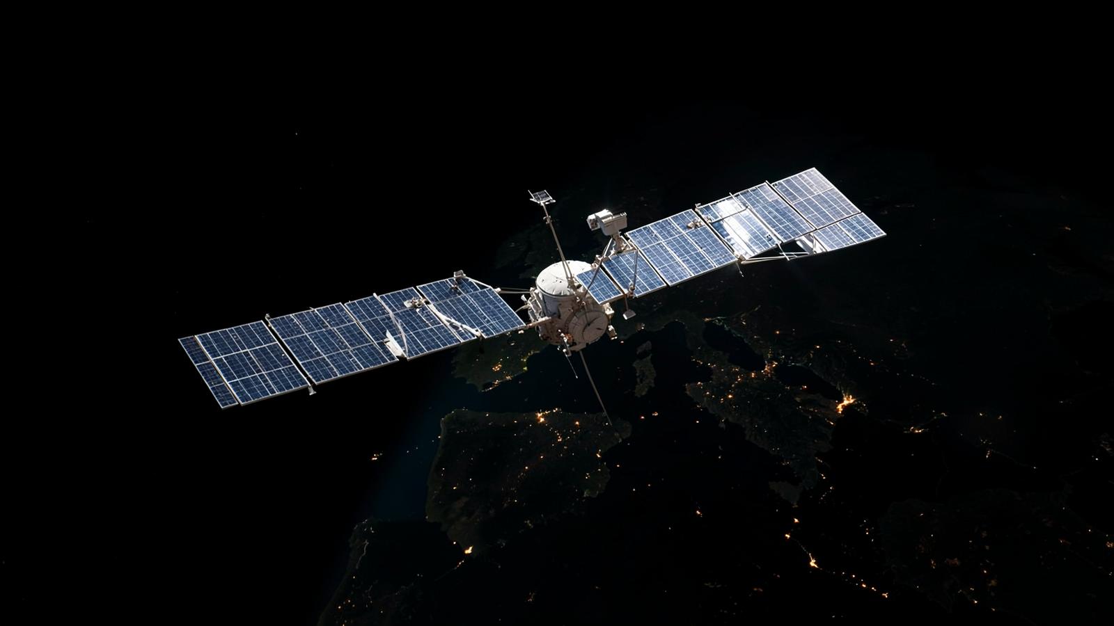 A satellite in orbit above Europe at night, sunlight on its solar panels.